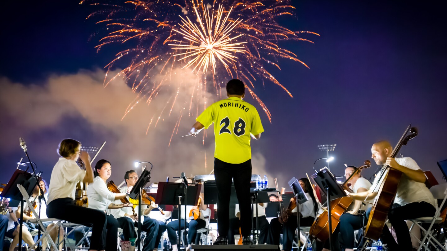 An image of the SC Philharmonic performing at Segra Park with fireworks lighting up the night sky.