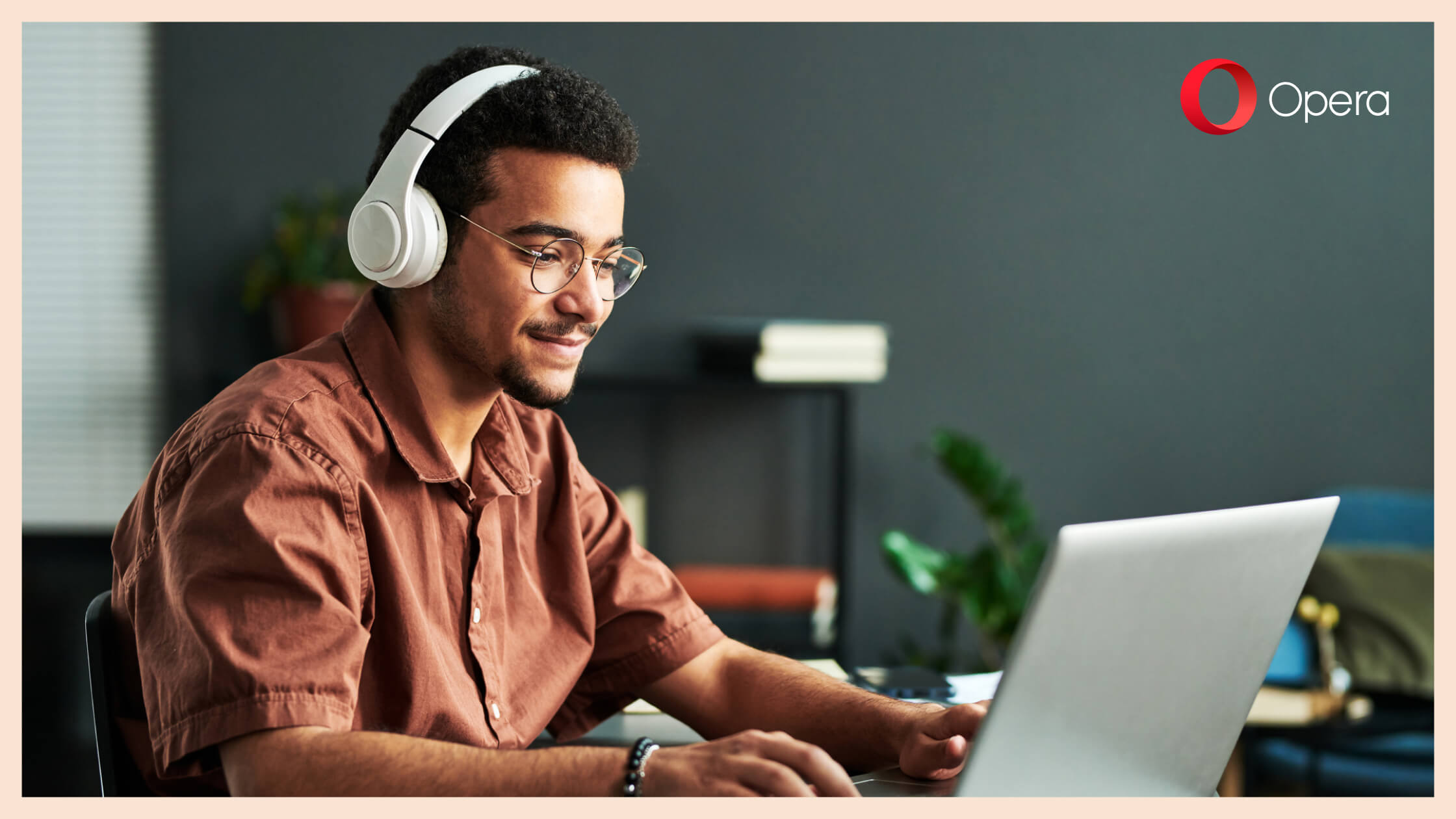 Ein junger Mann mit Kopfhörern arbeitet an seinem Laptop