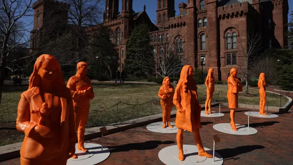 Seven orange statues stand on the Smithsonian Castle grounds.