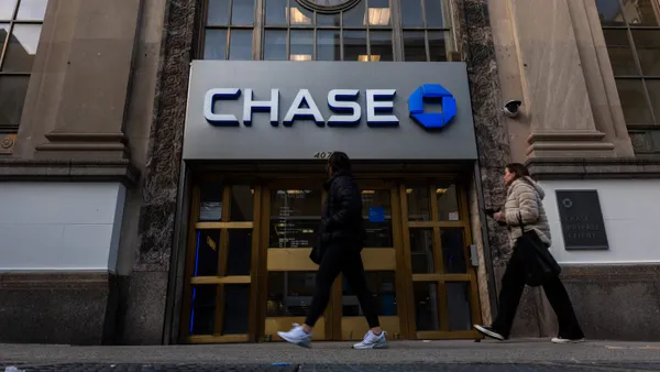 Two people walk past a Chase bank branch.