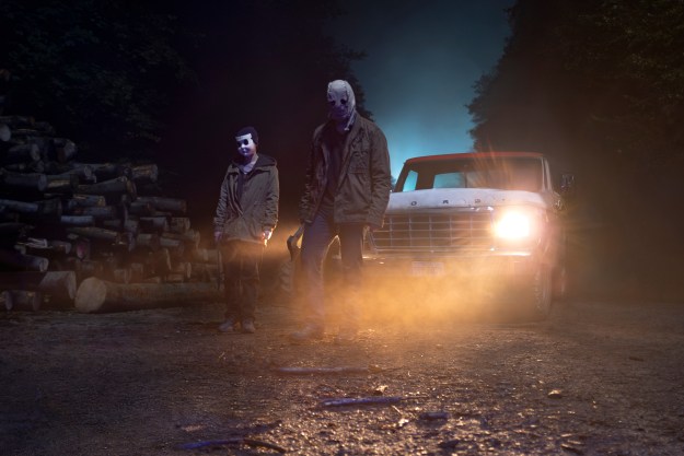 Two masked killers stand near a truck in The Strangers: Chapter 1.