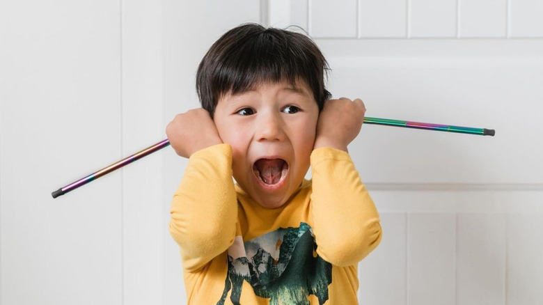 Child holding two straws up to ears