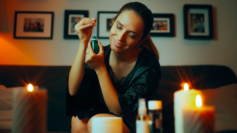 Smiling woman using essential oil dropper