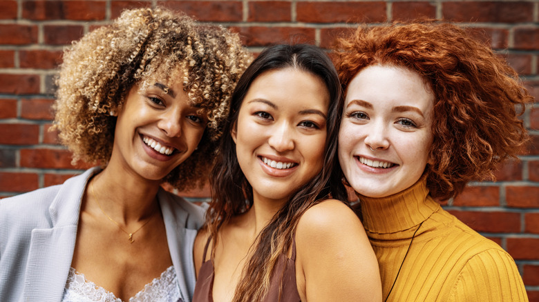 Three smiling women with different hair colors