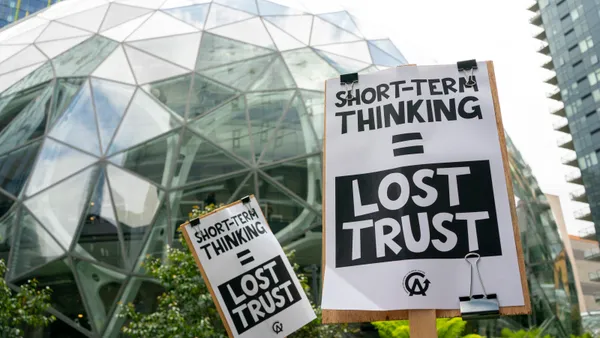 Two protest signs, in front a glass dome, read SHORT-TERM THINKING = LOST TRUST