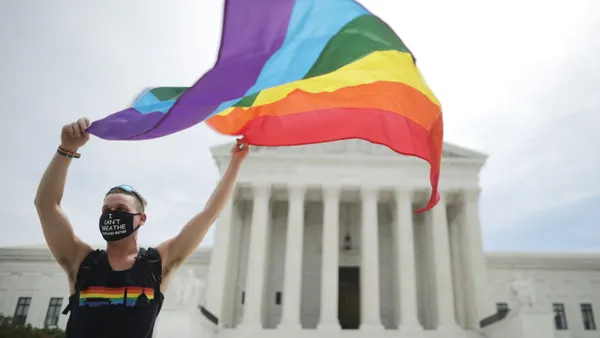 The LGBTQ+ pride flag flies in the hands of an activist.