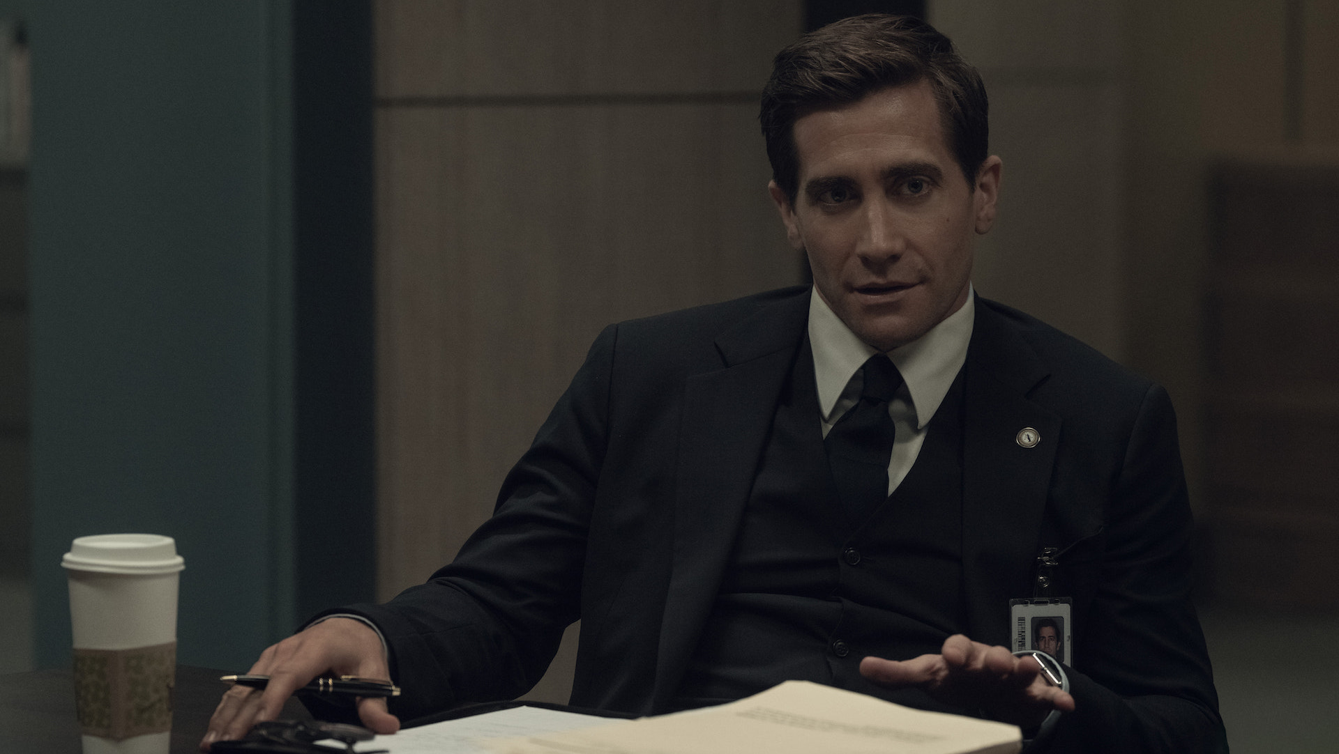 A man wearing a suit and sitting with pen and paper; Jake Gyllenhaal in 'Presumed Innocent'