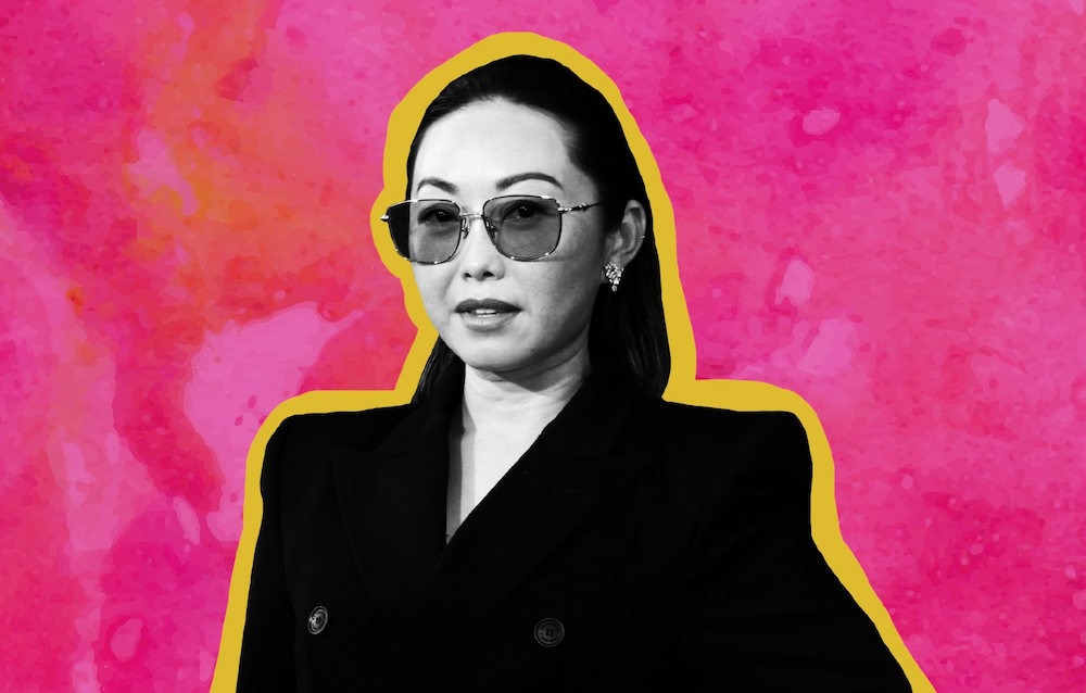 Lulu Wang wearing a blazer and sunglasses, shown here in black-and-white with a bright pink backdrop and a yellow outline
