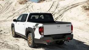 The rear of a white Honda Ridgeline on a dirt hill. The Ridgeline and Santa Cruz are competitors in the compact truck space.