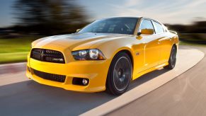 A yellow 2012 Dodge Charger driving in close left front angle view