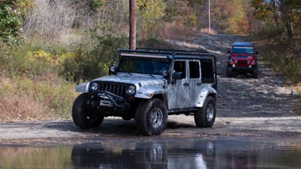 Jeep Wranglers Off-Roading Adventures near a stream in the woods.