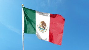 Mexican flag on a pole, a blue sky visible in the background.