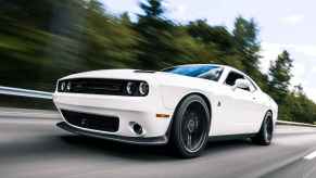 A white Dodge Challenger driving fast on the freeway in left front angle view facing left frame
