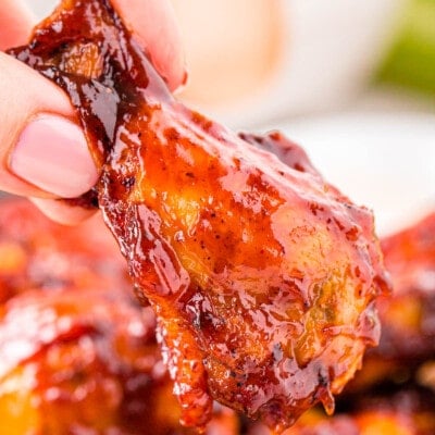 hand holding a chicken wing made in the air fryer and brushed with barbecue sauce.