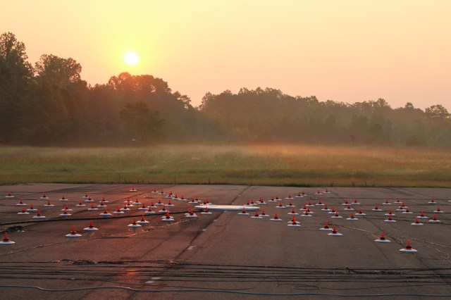 An array of microphones on an airfield, with a sunrise in the background