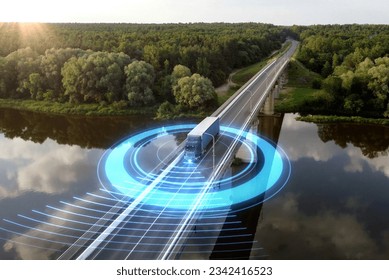 Autonomous semi-truck with a trailer, controlled by artificial intelligence, drives over a bridge over the river. Cargo delivery, transportation of the future. Artificial intelligence. Self driving.
 Stock Photo