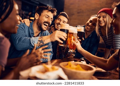 Multiracial group of happy friends having fun while toasting with beer in a bar. Stock Photo