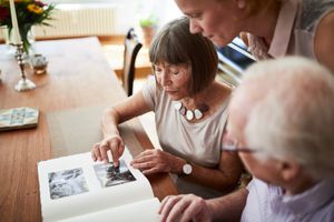 Older woman pointing at photograph and sharing the memories with her family.