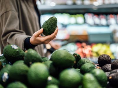 Man picking up avocado in grocery store