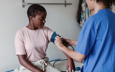 young woman having her blood pressure taken by nurse