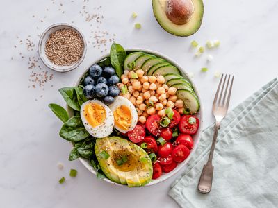 Overhead shot of bowl with berries, tomatoes, eggs, and avocado