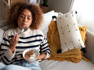 Relaxed happy female eating a granola and yogurt breakfast