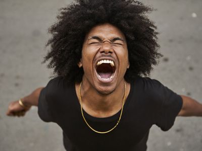 Dark skinned man with afro looking up yelling with mouth open and eyes closed