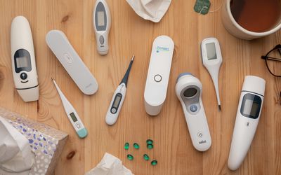 A variety of thermometers for at-home use side-by-side on a wood surface