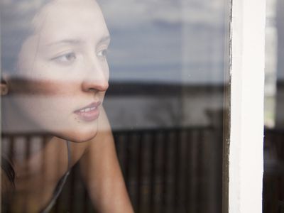 Woman looking out window. Avoidant personality disorder can lead to isolation.