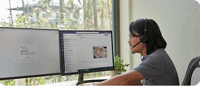 En mann som sitter ved et skrivebord med to skjermer og mobile enheter og arbeider eksternt fra hjemmekontoret sitt