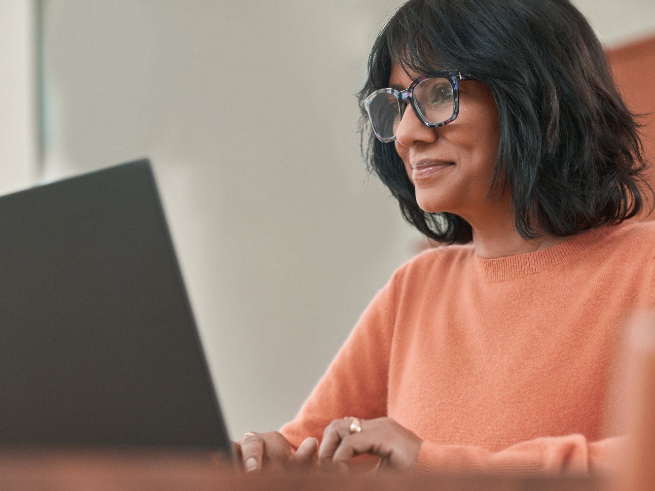 Uma mulher com óculos a trabalhar com um portátil