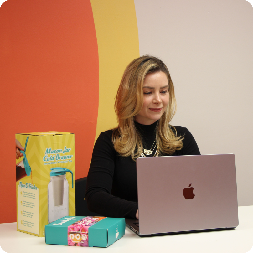 Jenni-Lyn Williams, CEO at SnarkyTea, working on her computer with SnarkyTea products beside her