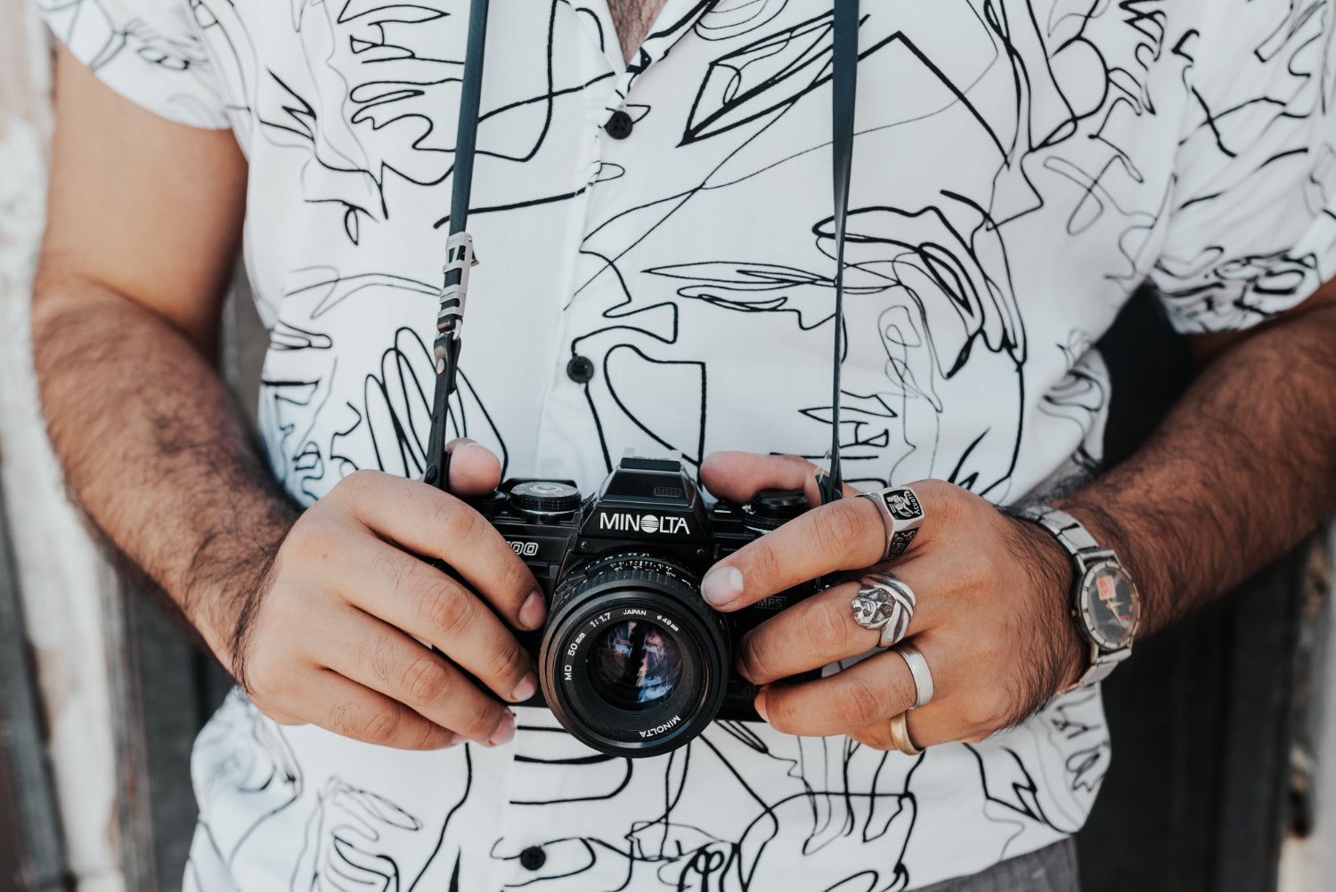 Crop of a person's torso. He is holding a digital camera