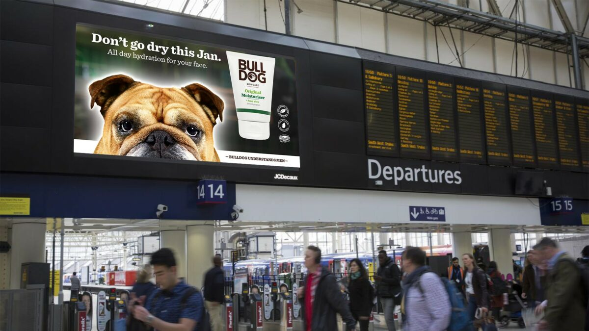Billboard at a train station featuring a bulldog’s head alongside a tube of moisturizer by Bulldog Skincare. The text reads “Don’t go dry this Jan.”