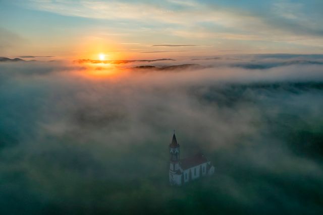 Wetterspektakel (25.5.2024) Morgendlicher Nebel über der Herz-Jesu-Kirche im ungarischen Sóshartyán. Für den Nordwesten des Landes sagt der ungarische Wetterdienst Regen und Gewitter voraus, für den Südosten Sonne und Temperaturen um 29 Grad Celsius.