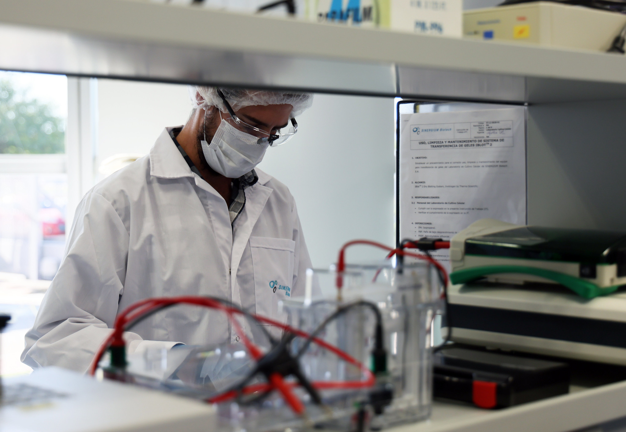 A person dressed in medical and protective clothing works in a medical lab.