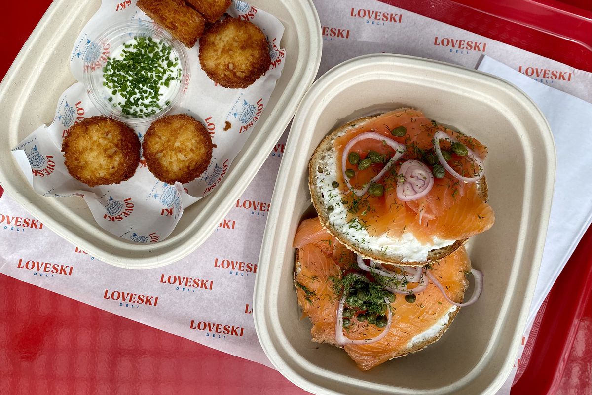 A sliced bagel with cream cheese, lox, and red onions, plus potato latkes, from Loveski Deli.