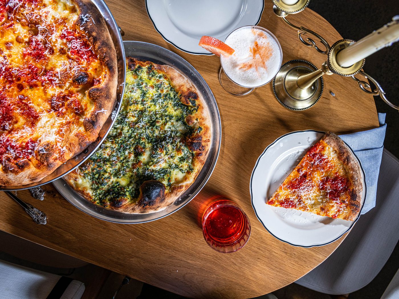 Two pizzas on a table, one with pepperoni and another with greens.