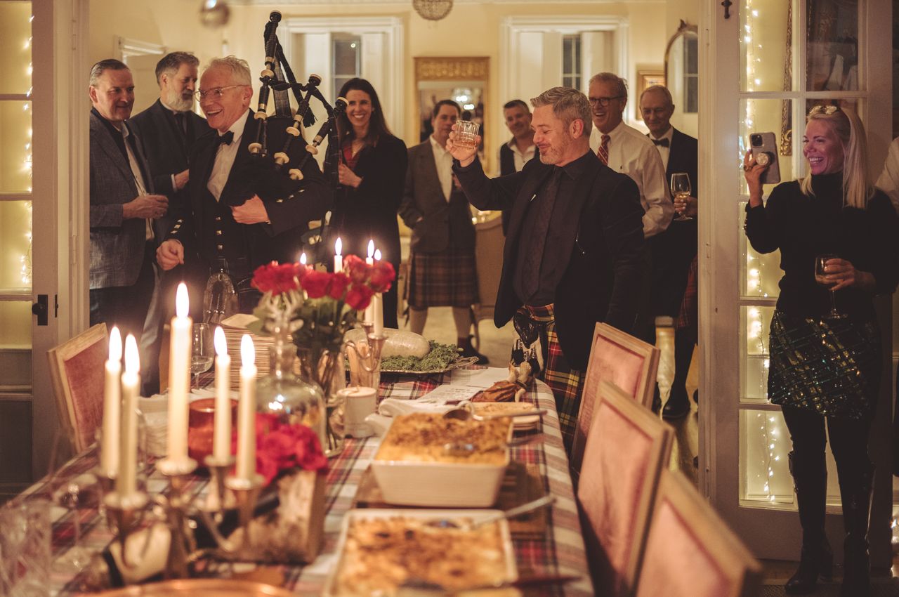 People in Scottish kilts gathered around a table with food and candles.