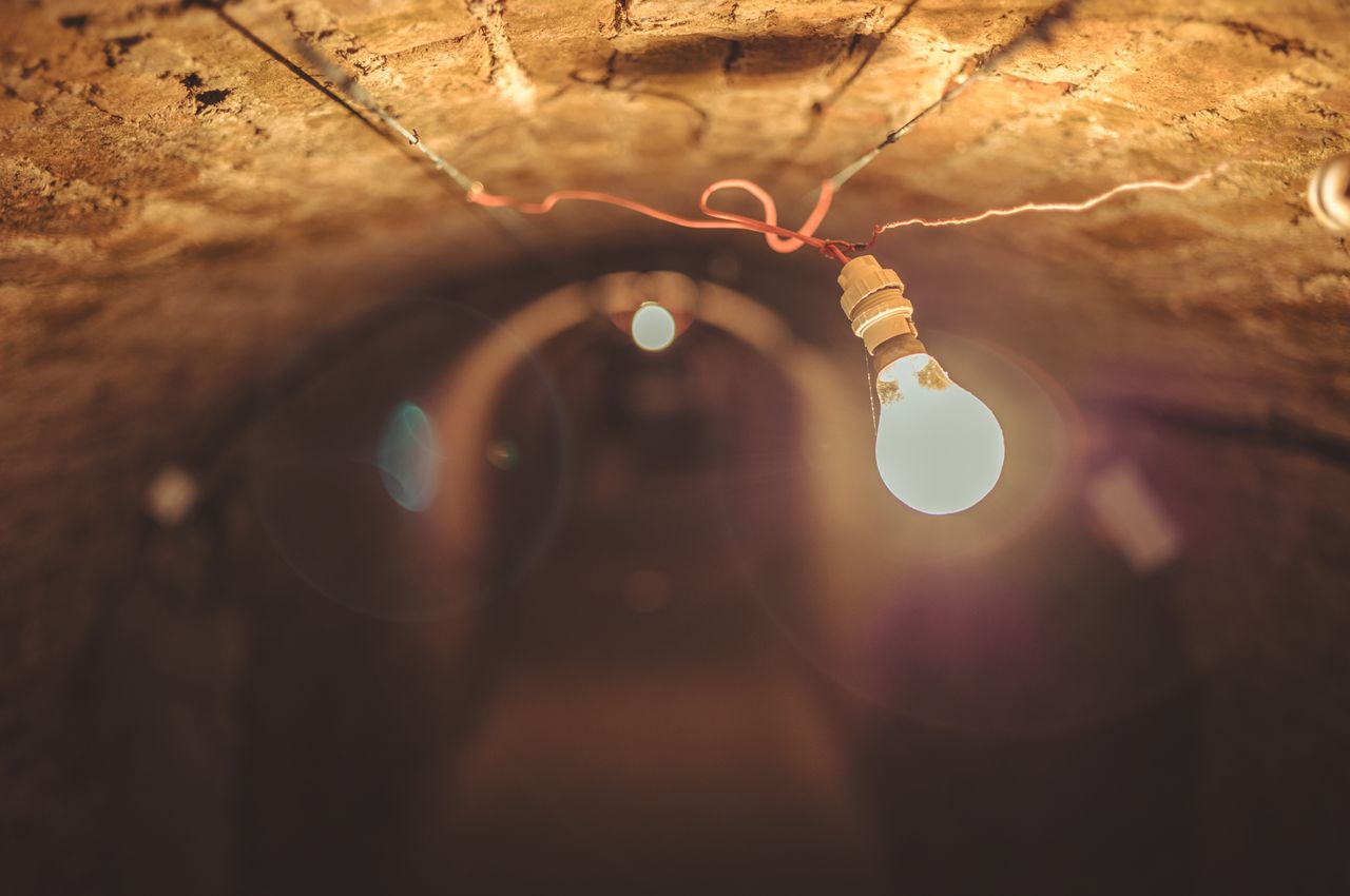 A glowing light bulb hanging in an underground tunnel.