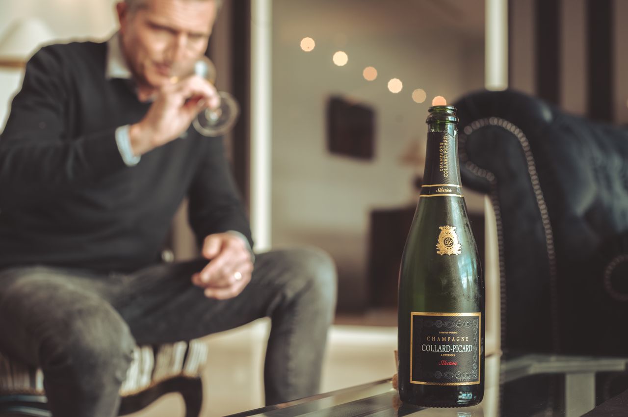 A bottle of Collard-Picard champagne with a person drinking champagne in the background.