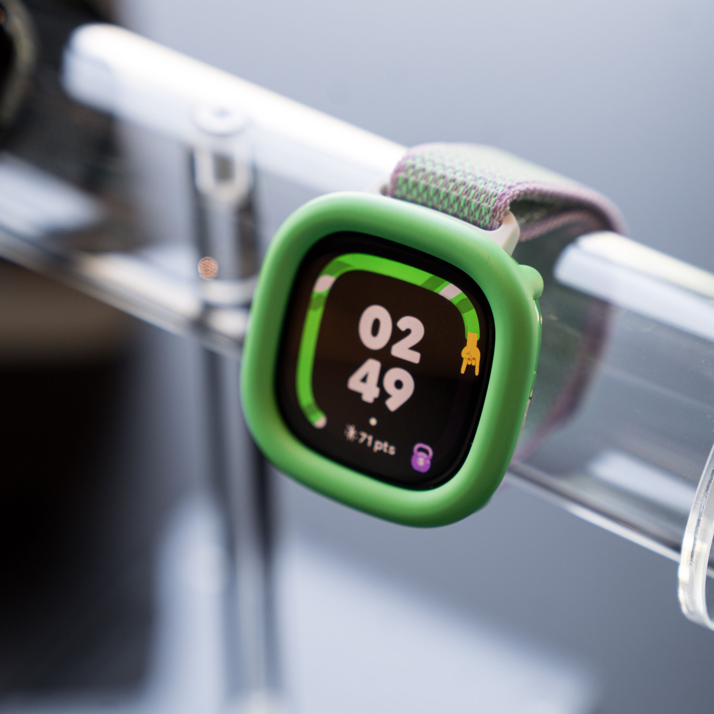 Close-up of the Fitbit Ace LTE in the Spicy Pebble variant with a neon green bumper.
