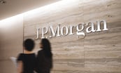 inside jpmorgan office with jpmorgan logo on wall while two people walk by_jpmorgan