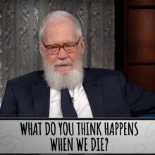 A man sits in a talk show chair. The question at the bottom of the screen reads "What do you think happens when we die?"