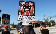 A union protestor holds up a sign that says "AI is yuck".