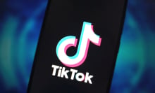 A phone screen displaying the TikTok logo in front of a blue backdrop. 