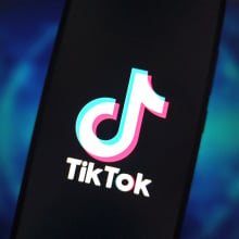 A phone screen displaying the TikTok logo in front of a blue backdrop. 