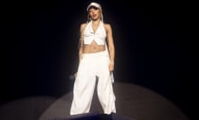 Tinashe performing at Coachella in a white vest, pants, and baseball cap. 
