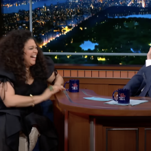 Michelle Buteau and Stephen Colbert giggle during an interview on "The Late Show."