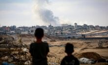 Boys watch smoke billowing during Israeli strikes east of Rafah in the southern Gaza Strip.